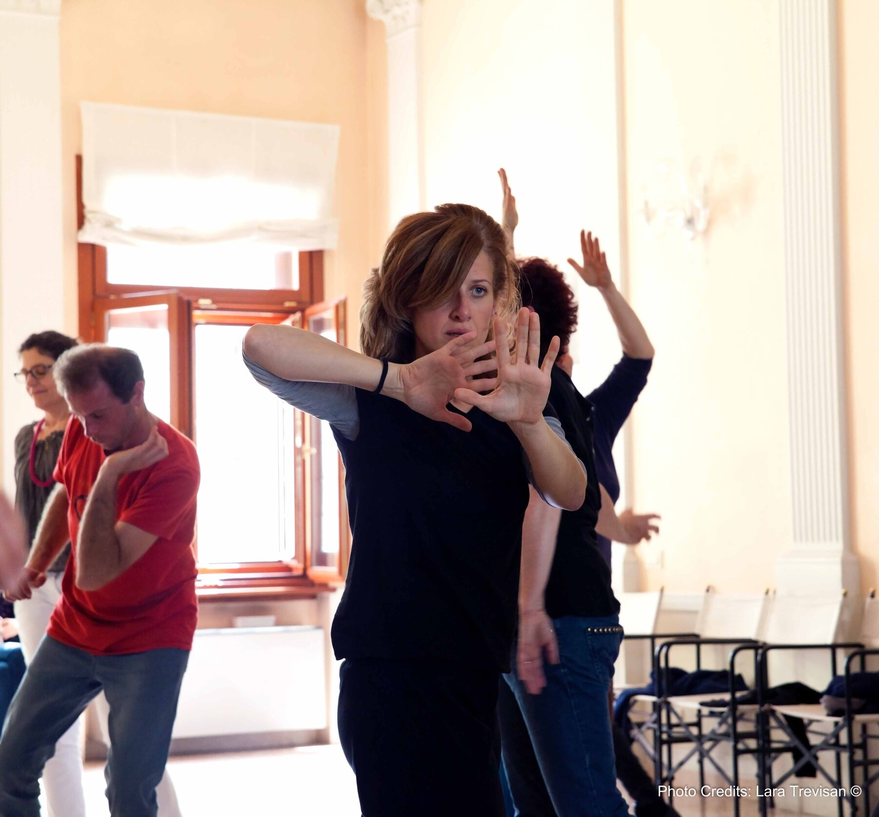 L'artista Caterina Comingio in primo piano e altre persone sullo sfondo, sperimentano l'interpretazione teatrale.