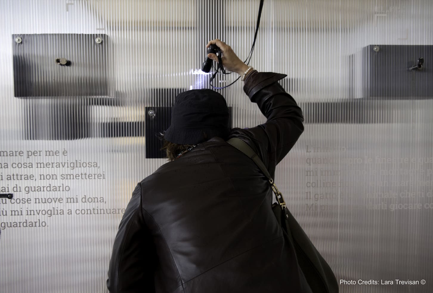 Una donna di spalle fruisce della visione di immagini attraverso l'interazione con un'installazione contemporanea.