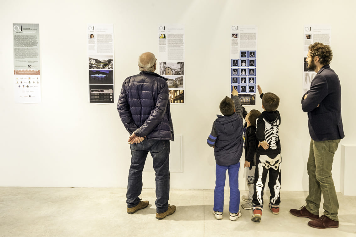 Due adulti e un bambino guardano l'esposizione del progetto "Vajont: reazione, progetto, resilienza".