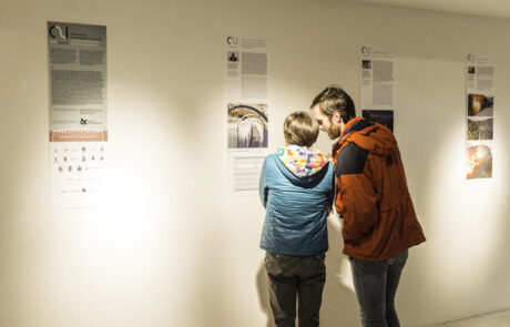 Un uomo e una donna guardano l'esposizione del progetto "Vajont: reazione, progetto, resilienza".